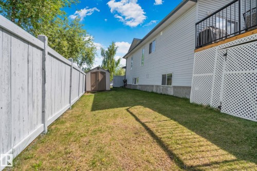 Rear exterior featuring light grey siding and a lattice-skirted deck with a black metal railing - 1 Hunt Court, St. Albert, AB 