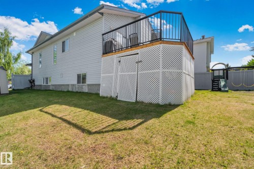 Spacious backyard with a raised wood-finish deck featuring black metal railings and white lattice skirting - 1 Hunt Court, St. Albert, AB 