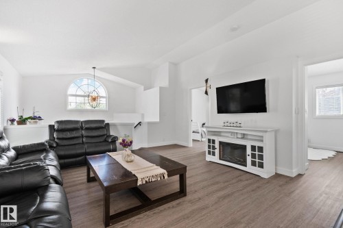 Living area featuring wood-finish flooring, vaulted ceilings, and an arched transom window - 1 Hunt Court, St. Albert, AB 