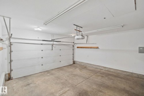 Spacious garage featuring a concrete floor, white walls, and a white paneled garage door - 1 Hunt Court, St. Albert, AB 