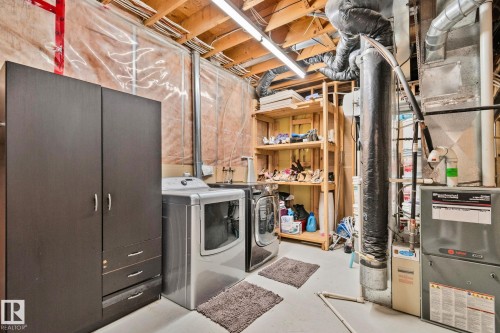 Utility area featuring a front-loading washer and dryer, exposed ceiling joists, and a furnace system - 1 Hunt Court, St. Albert, AB 