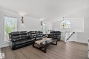 Vaulted ceiling living area featuring wood-finish flooring, a prominent arched window, and a white painted railing - 1 Hunt Court, St. Albert, AB 