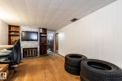 Family room in basement with built in shelves and fireplace, and unfinished floors - 