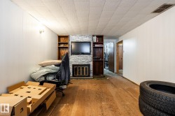 Family room in basement with built in shelves and fireplace, and unfinished floors - 