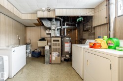 Laundry room with washer and dryer, wood walls, light floors, gas water heater, and furnace - 