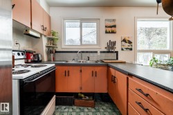 Kitchen featuring range with electric stovetop, open shelves, dark countertops, and stainless steel fridge - 