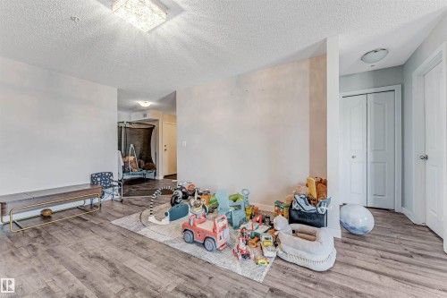 Spacious room with wood-finish flooring, white walls, and a textured ceiling - 320 534 Watt Boulevard, Edmonton, AB - Indoor Photo Showing Other Room