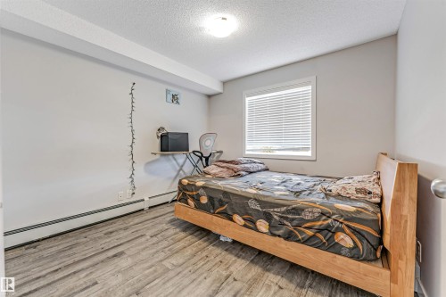 Neutral wall paint, wood-finish flooring, and a single window with blinds - 320 534 Watt Boulevard, Edmonton, AB - Indoor Photo Showing Bedroom