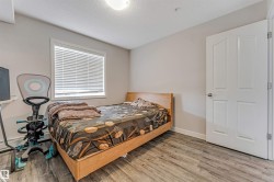 Bedroom featuring wood-finish flooring, a double-panel interior door, and a window with blinds - 