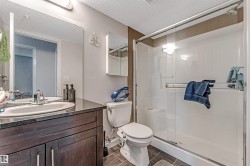 Bathroom featuring a dark wood-finish vanity with an undermount sink and dark countertop, a large wall-mounted mirror, and a glass-enclosed shower with white paneling and a built-in shelf - 