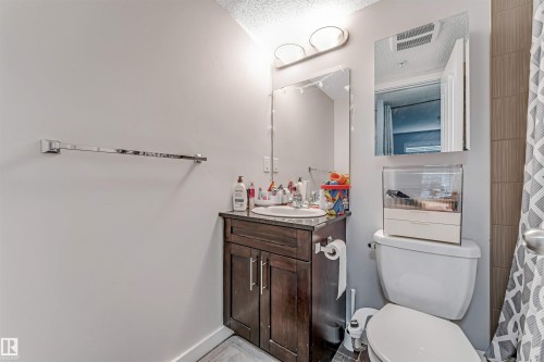 Bathroom featuring a dark wood-finish vanity with a white basin sink, a wall-mounted mirror, and a chrome towel bar - 320 534 Watt Boulevard, Edmonton, AB - Indoor Photo Showing Bathroom