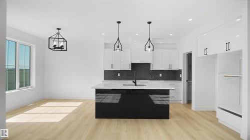 Modern kitchen featuring a black central island with a white countertop, white upper and lower cabinetry, and a dark geometric tile backsplash - 803 30 Avenue, Edmonton, AB 