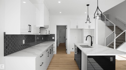 Contemporary kitchen featuring white cabinetry, a black geometric tile backsplash, light wood-finish flooring, a kitchen island with an undermount sink, and black pendant lighting - 803 30 Avenue, Edmonton, AB 