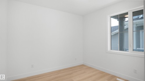 Bright room featuring light wood-finish flooring, white walls, and a large window with white trim - 803 30 Avenue, Edmonton, AB 