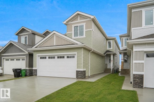 Contemporary exterior featuring light green horizontal siding and stacked stone accents - 803 30 Avenue, Edmonton, AB 