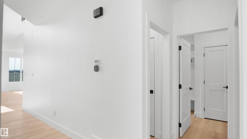 Hallway featuring light wood-finish flooring, white walls, and contemporary black door hardware - 803 30 Avenue, Edmonton, AB 