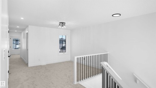 Carpeted landing featuring a contemporary flush mount light fixture, recessed lighting, and a white and black spindle stair railing - 803 30 Avenue, Edmonton, AB 