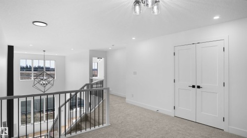 Second-story landing with light-toned carpet flooring, recessed lighting, and a modern chandelier - 803 30 Avenue, Edmonton, AB 