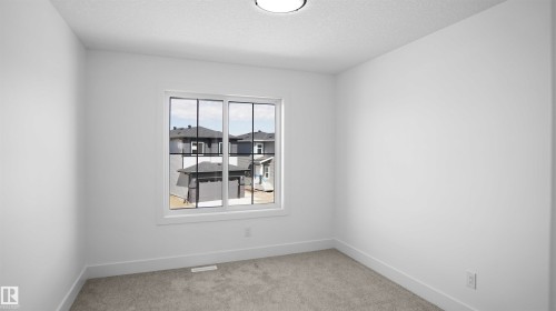 Bright interior space featuring a multi-pane window, neutral-toned carpeting, white walls, and a flush-mount ceiling light fixture - 803 30 Avenue, Edmonton, AB 