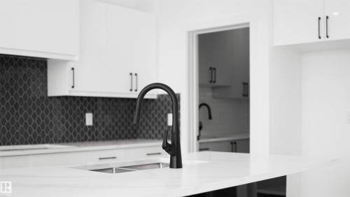 Kitchen featuring white cabinetry, a black matte gooseneck faucet, an undermount double-basin sink, and a dark mosaic tile backsplash - 803 30 Avenue, Edmonton, AB 