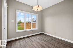 Expansive window with grid panes, wood-finish flooring, neutral wall paint, white baseboards, and a contemporary ceiling fixture - 
