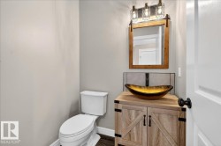 Wood-finish vanity featuring barn door detailing, a vessel sink, and a rustic wood-framed mirror - 
