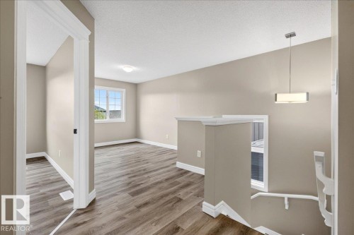 Open concept upper level featuring wood-finish flooring, neutral paint tones, and window with exterior view - 62 Durrand Bend, Fort Saskatchewan, AB 