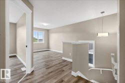 Open concept upper level featuring wood-finish flooring, neutral paint tones, and window with exterior view - 