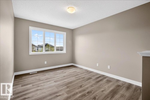 Bright interior space featuring a large multi-pane window, wood-finish flooring, and neutral wall tones - 62 Durrand Bend, Fort Saskatchewan, AB 