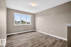 Bright interior space featuring a large multi-pane window, wood-finish flooring, and neutral wall tones - 