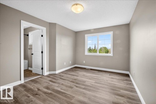 Interior room featuring wood-finish flooring, neutral wall tones, and white trim - 62 Durrand Bend, Fort Saskatchewan, AB 