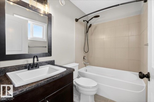 Bathroom featuring a white vanity with dark stone-finish countertop, undermount sink, and matte black faucet - 62 Durrand Bend, Fort Saskatchewan, AB 
