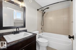Bathroom featuring a white vanity with dark stone-finish countertop, undermount sink, and matte black faucet - 