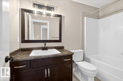 Full bathroom featuring a dark wood-finish vanity with a built-in sink, a dark countertop, and a shower-tub combination - 62 Durrand Bend, Fort Saskatchewan, AB 