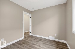 Room featuring wood-finish flooring, neutral wall paint, white baseboards, and a white window frame - 