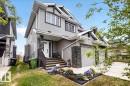 Two-story residence featuring light gray horizontal siding, dark gray trim, and stone veneer accents - 62 Durrand Bend, Fort Saskatchewan, AB 
