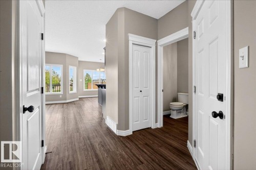 Spacious interior featuring wood-finish flooring throughout, light gray wall paint, and white trim - 62 Durrand Bend, Fort Saskatchewan, AB 