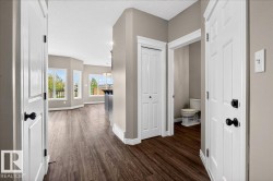 Spacious interior featuring wood-finish flooring throughout, light gray wall paint, and white trim - 