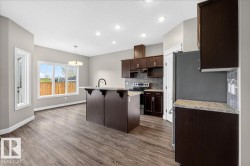 Open-concept kitchen and dining area featuring dark wood-finish cabinetry, light-toned countertops, and a subway tile backsplash - 