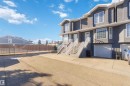 Multi-level townhome exterior featuring grey stucco siding, white trim, and prominent bay windows - #8 15128 22 St Nw, Edmonton, AB 