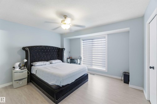Spacious room with wood-finish flooring, a ceiling fan with integrated lighting, and light blue walls - 8 15128 22 Street, Edmonton, AB 