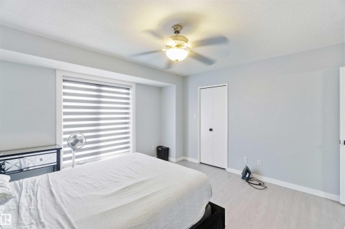 Light gray walls with white trim, wood-finish flooring, and a ceiling fan with integrated lighting - 8 15128 22 Street, Edmonton, AB 