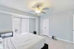 Light gray walls with white trim, wood-finish flooring, and a ceiling fan with integrated lighting - 