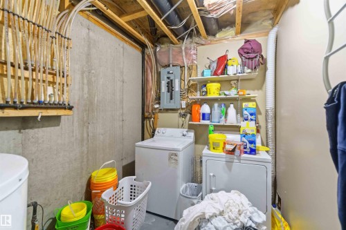 Dedicated laundry area featuring a washer and dryer, exposed structural beams, and a concrete foundation wall - 8 15128 22 Street, Edmonton, AB 