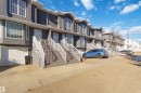 Townhome exterior featuring a stucco finish, multi-pane windows, white railings, and a single-car garage - 8 15128 22 Street, Edmonton, AB 
