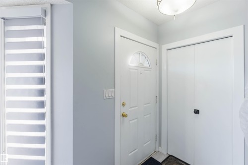 Entryway featuring a white paneled door with an arched transom window, brass hardware, and an overhead flush-mount light fixture - 8 15128 22 Street, Edmonton, AB 