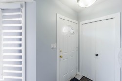 Entryway featuring a white paneled door with an arched transom window, brass hardware, and an overhead flush-mount light fixture - 