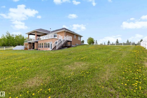 Expansive grassy yard with a white fence bordering the property - 28125 Highway 587, Rural Red Deer County, AB 