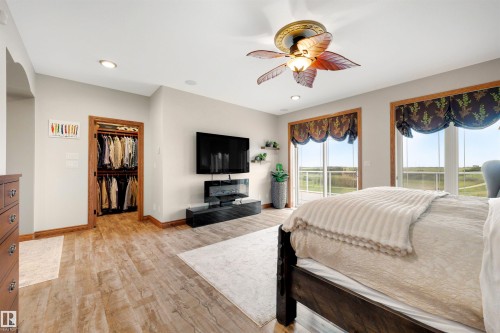 Spacious room featuring wood-finish flooring, recessed lighting, and a decorative ceiling fan - 28125 Highway 587, Rural Red Deer County, AB 