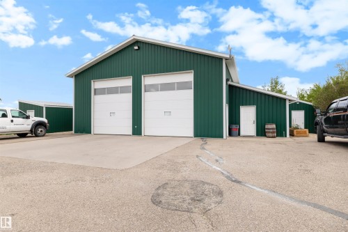 Metal-sided building with two large white overhead doors, an additional entry door, and a concrete apron - 28125 Highway 587, Rural Red Deer County, AB 